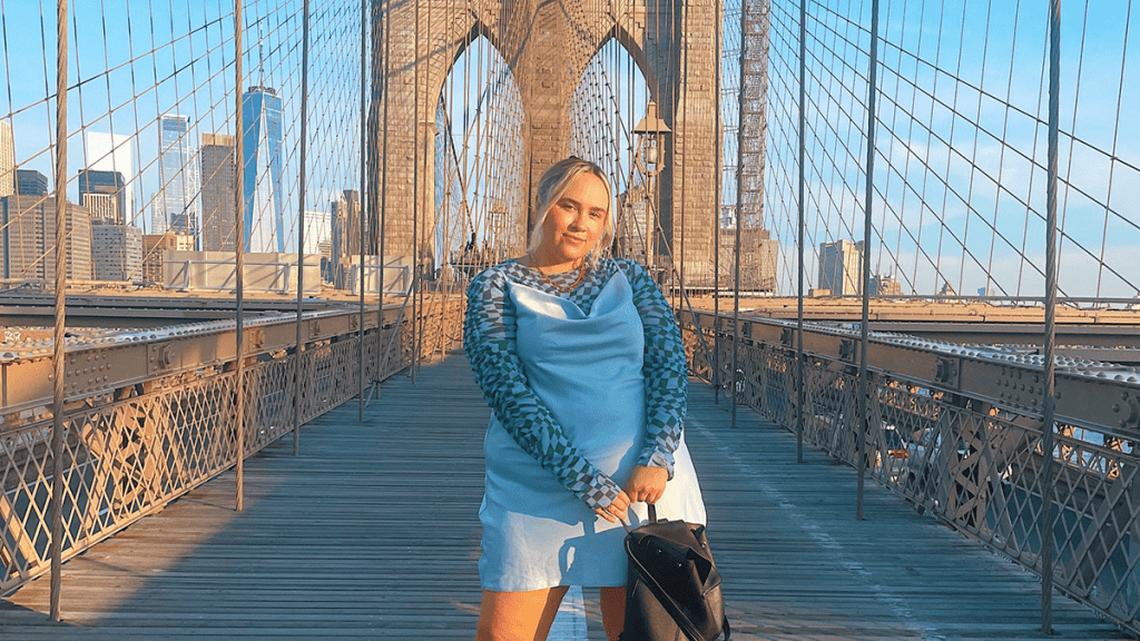 blonde woman in light blue dress standing on Brooklyn Bridge