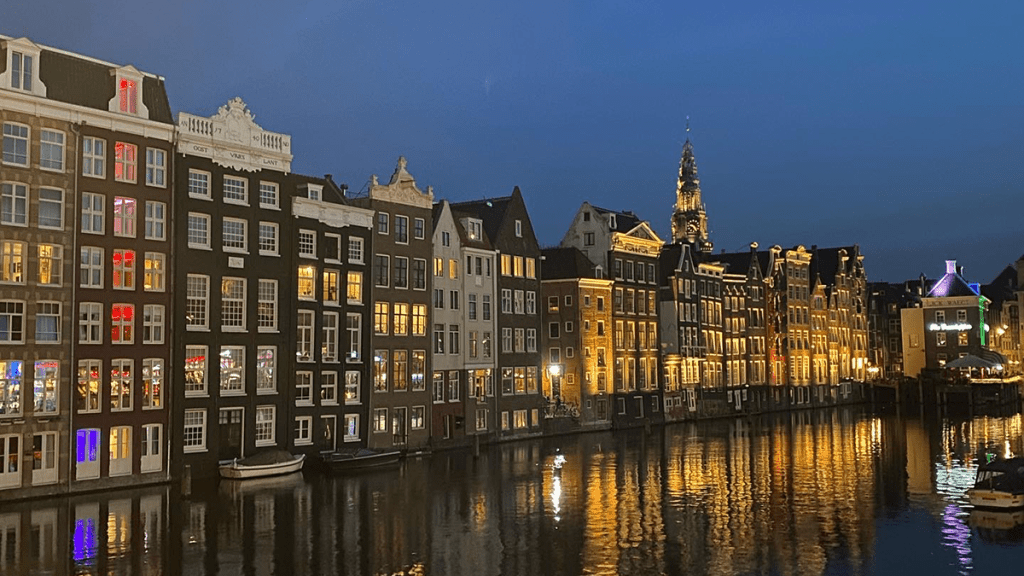 European buildings at dusk with lights on, sitting along river