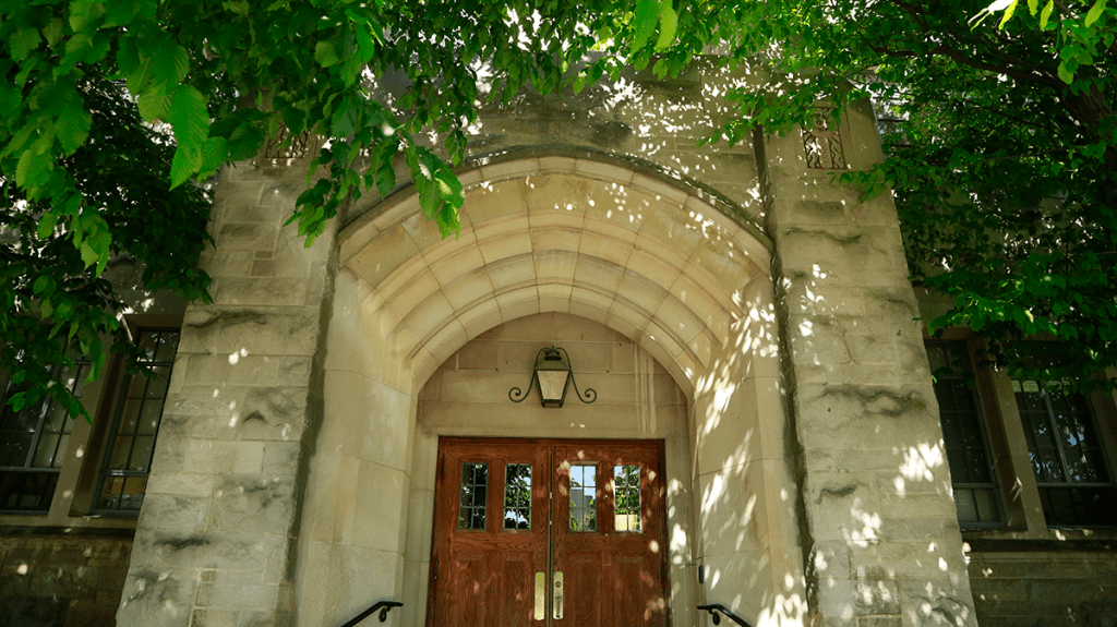 Pharmacy Building arched entrance, limestone brick, wood door, canopy of green leaves above