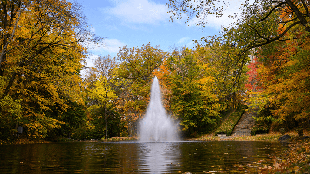 Lake at Holcomb Gardens with fountain and multi-colored fall trees