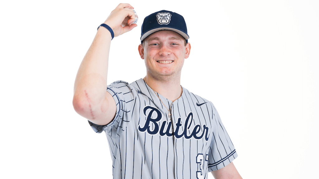 male in baseball uniform with Butler on front, hat with Bulldog logo