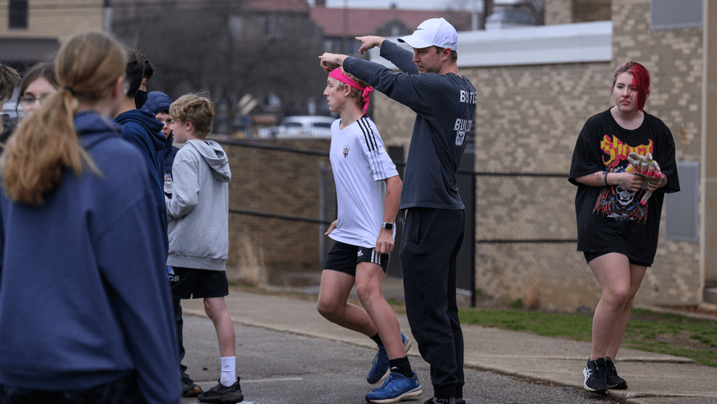 Male Butler college student in blue shirt and white hat coaching high school soccer players