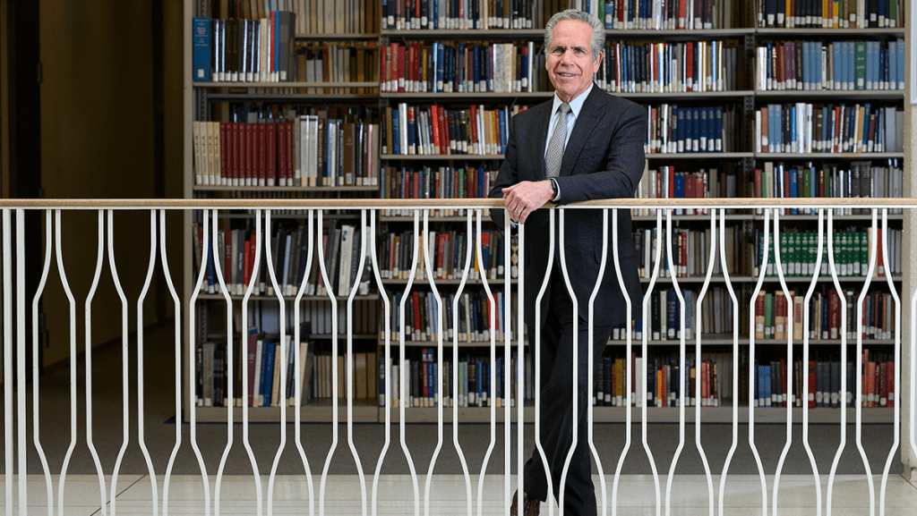 President James Danko in front of book shelves in Irwin Library