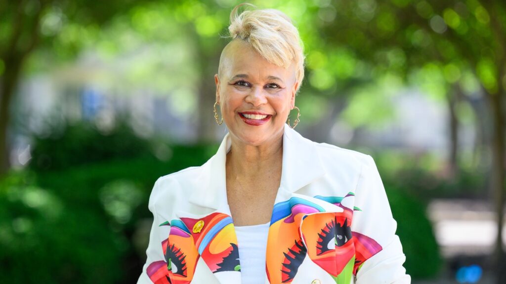 Linda Calvin ’00 standing outside on Butler's campus, wearing a white blazer with a brightly colored design across the middle.