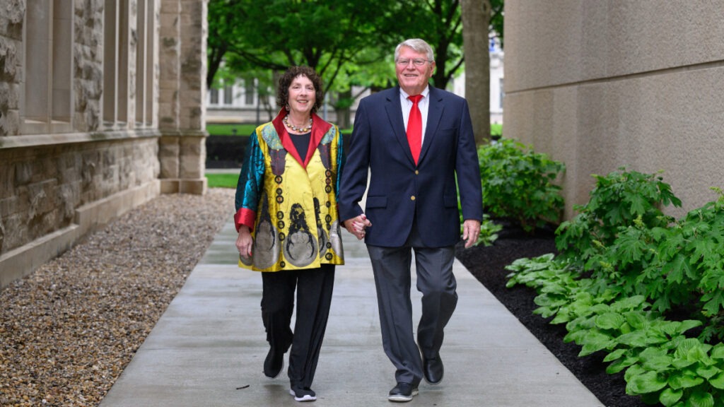 Marianne Glick and Mike Woods holding hands and walking on Butler's campus.