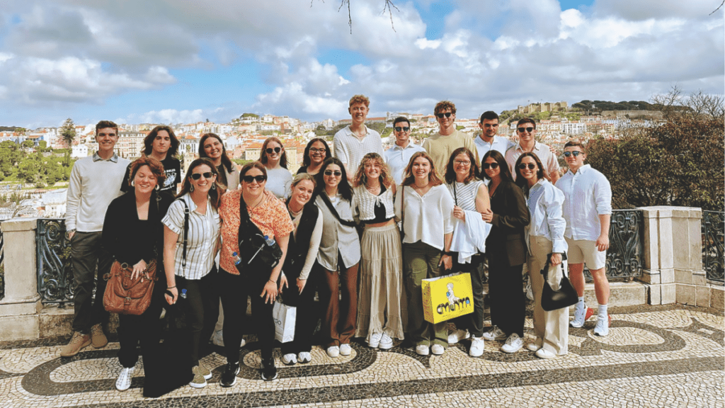 A group of twenty Butler students and faculty posing on a scenic overlook in Lisbon, Portugal, with a cityscape in the background.