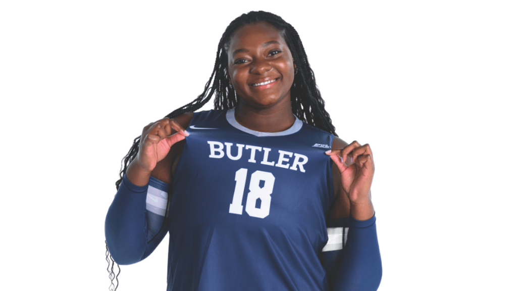 Destiny Cherry smiling and holding the edges of her navy volleyball jersey with "BUTLER" and the number "18" on it.