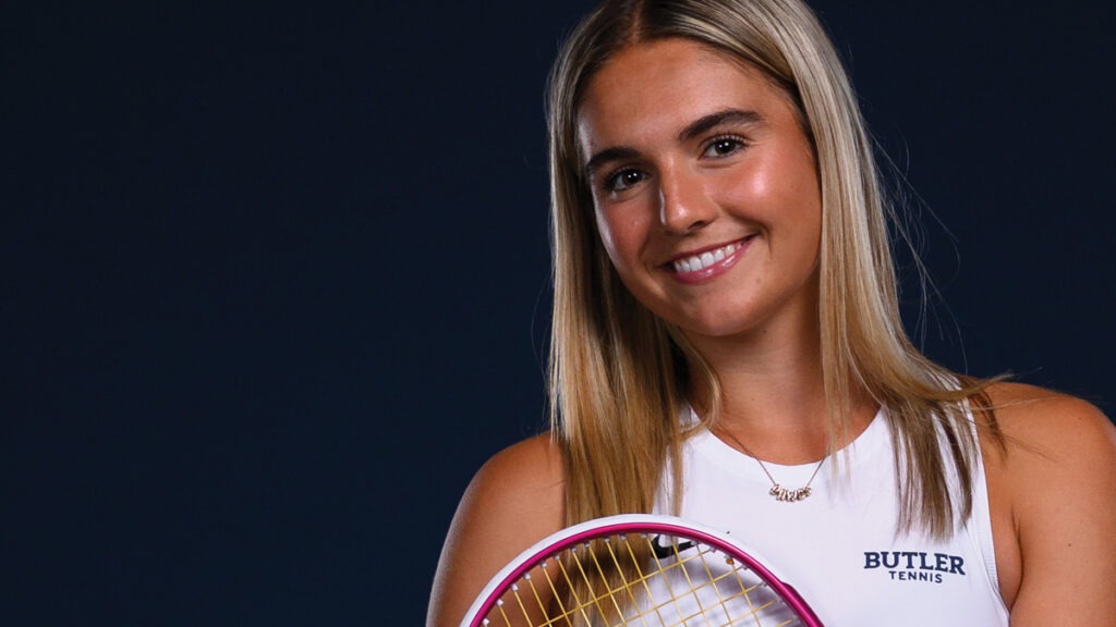 Butler tennis player Chase Metcalf smiles while holding tennis racket.