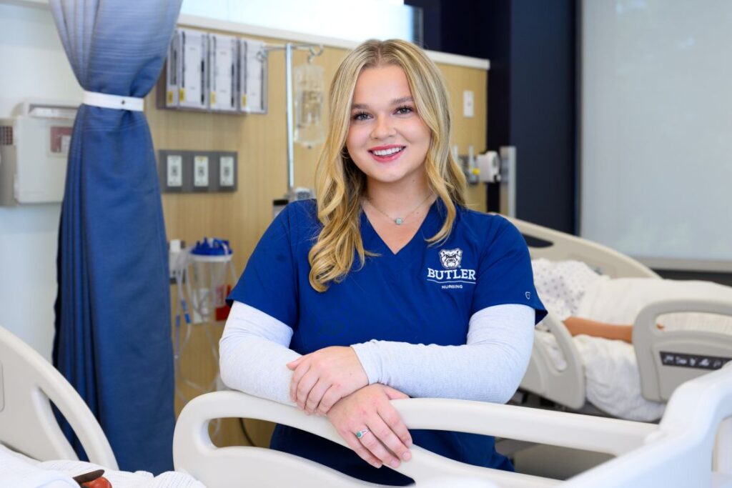 Amelia Buhner in a blue Butler University shirt sitting in a practice hospital room