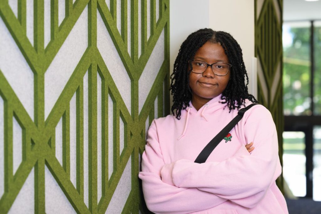 Image of Emmanuelle Wagnac in a pink shirt against a wall with a green pattern on the wall