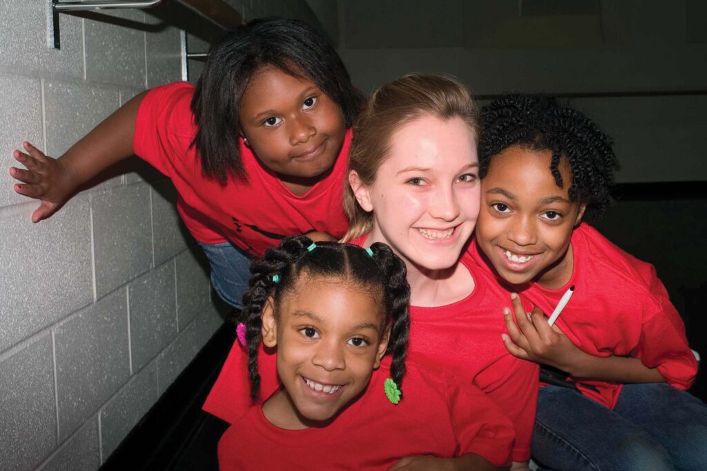 Young woman surrounded by smiling children.