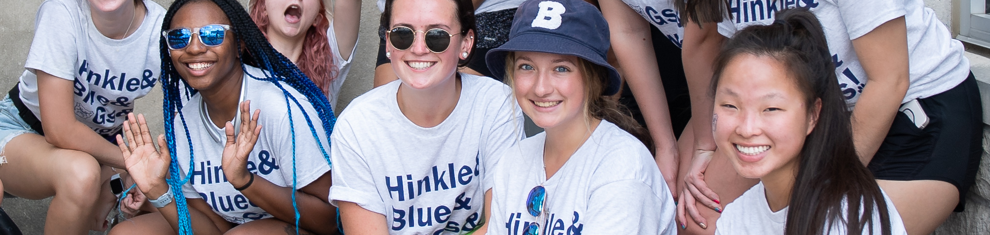 four students wearing the same butler shirt and smiling