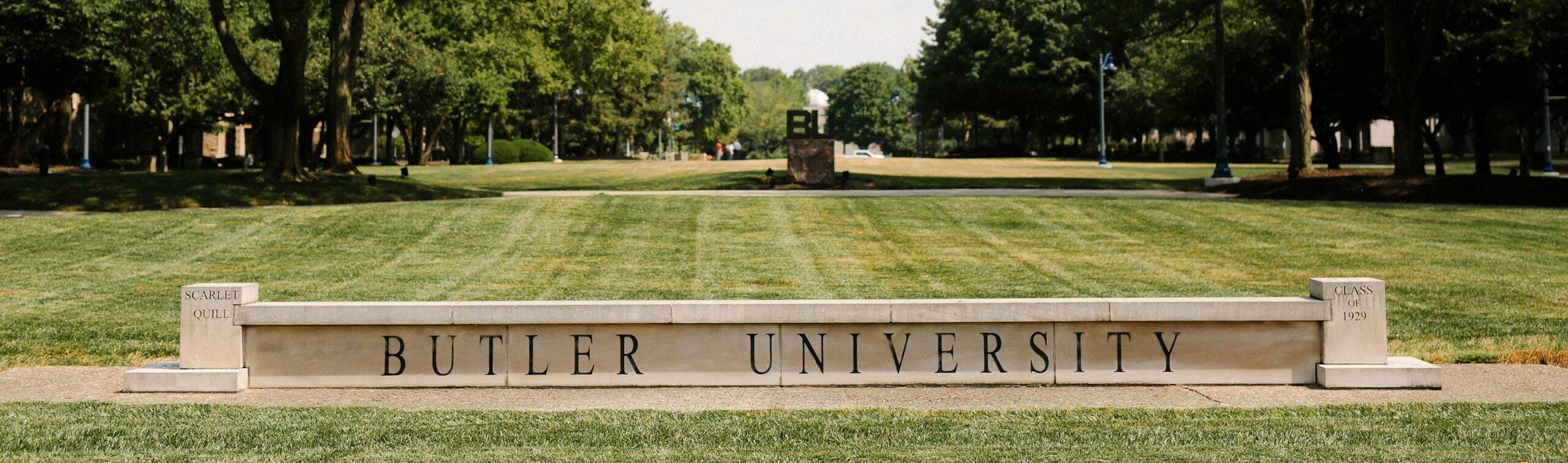 Large green grass lawn on Butler's campus with concrete sign of Butler University