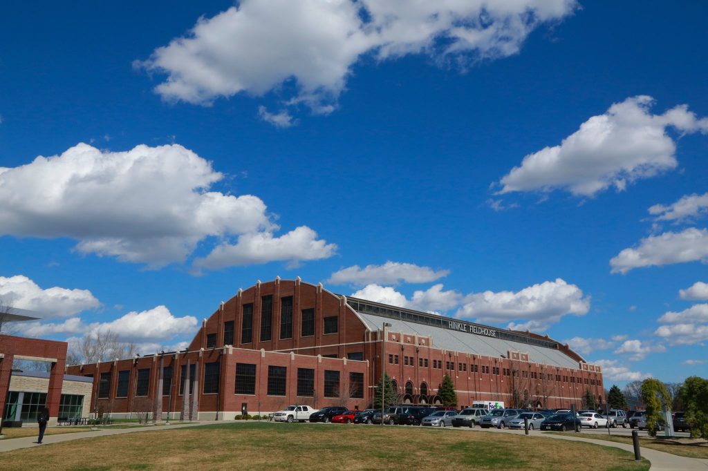 Large brick building with words "Hinkle Fieldhouse" and white clouds in a blue sky.
