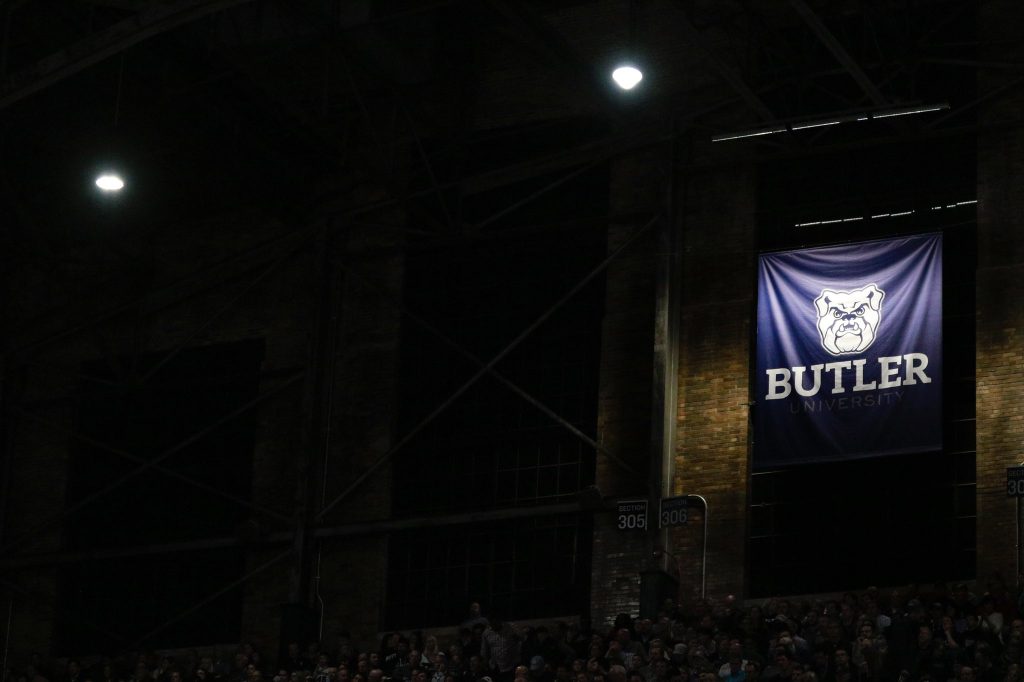 Dark interior of Hinkle Fieldhouse with lights off except for spotlight on a large Butler Bulldog logo banner.