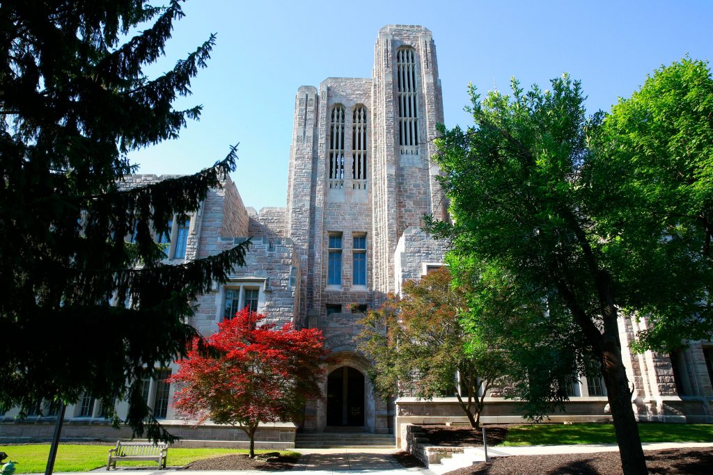 Entrance of limestone brick Jordan Hall academic building with autumn trees in front of it.