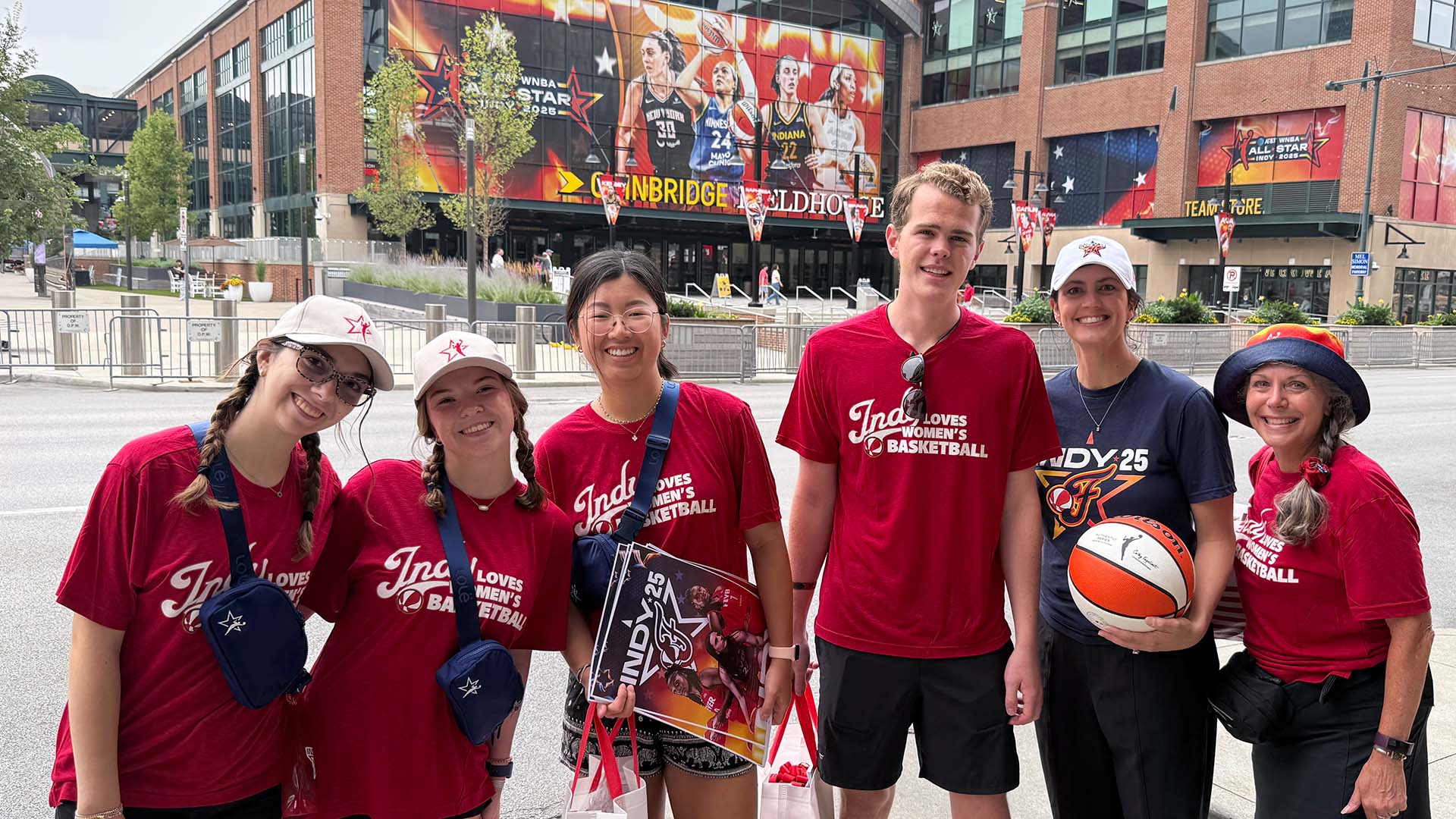 Several member of the Butler BISE street team pose for a group photo with swag outside Gainbridge Fieldhouse during WNBA All-Star Game festivities