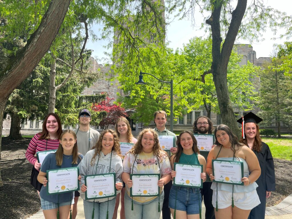 Class of 2025 Green Grads showing off green cords and completion certificates