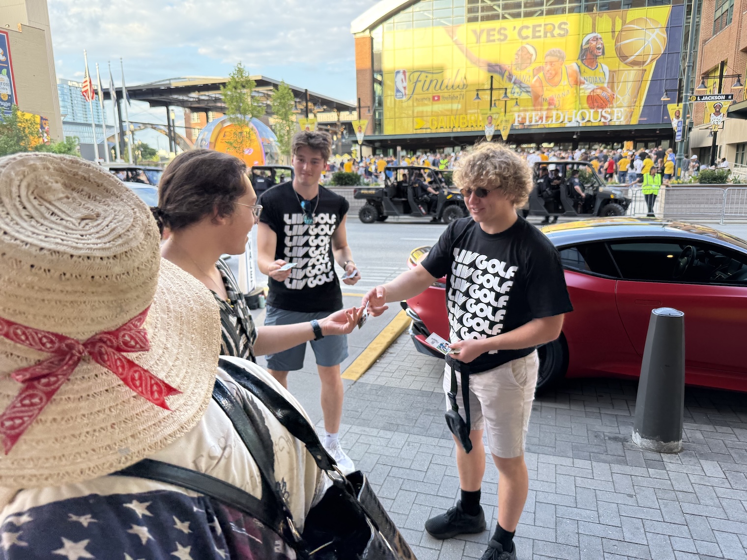 Butler students give handouts to people on the sidewalk to promote the LIV Golf tournament while outside Gainbridge Fieldhouse during the NBA Finals.
