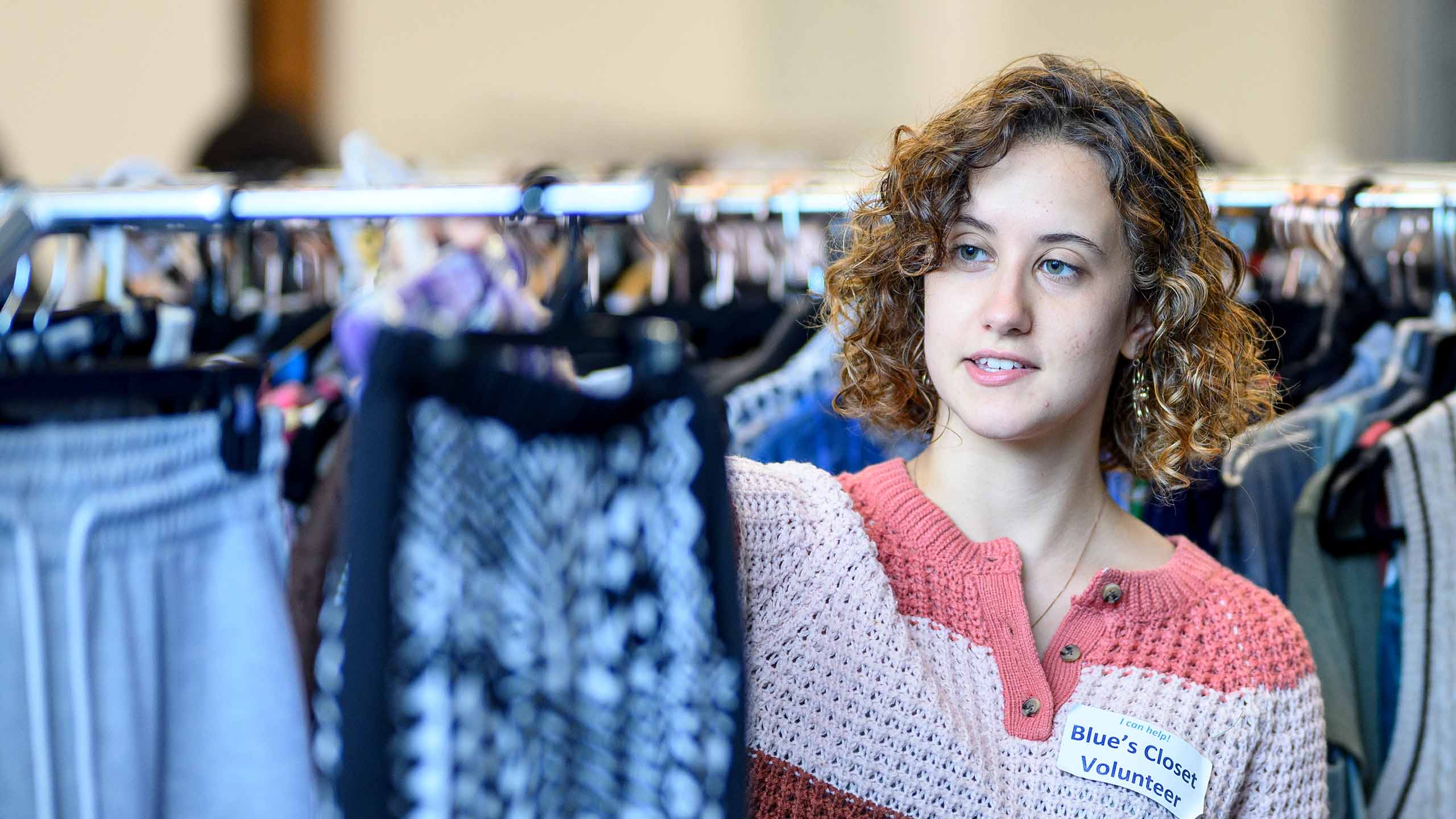 Blue's Closet female volunteer looks at clothes on racks.