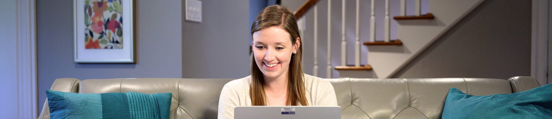 Female student smiles while working on laptop at home.