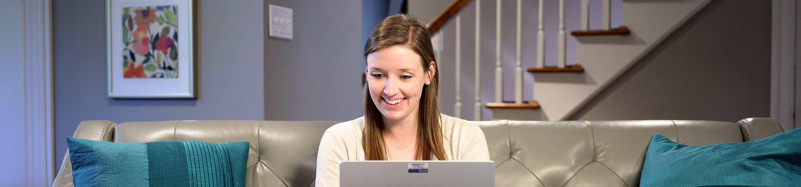 Female student smiles while working on laptop at home.