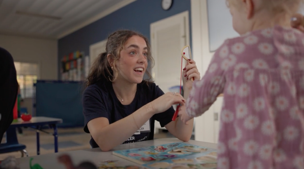 A Butler student helping a elementary school girl with an early language and literacy activity. 