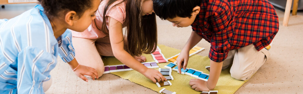 Children playing colorful game on floor in a montessori school.