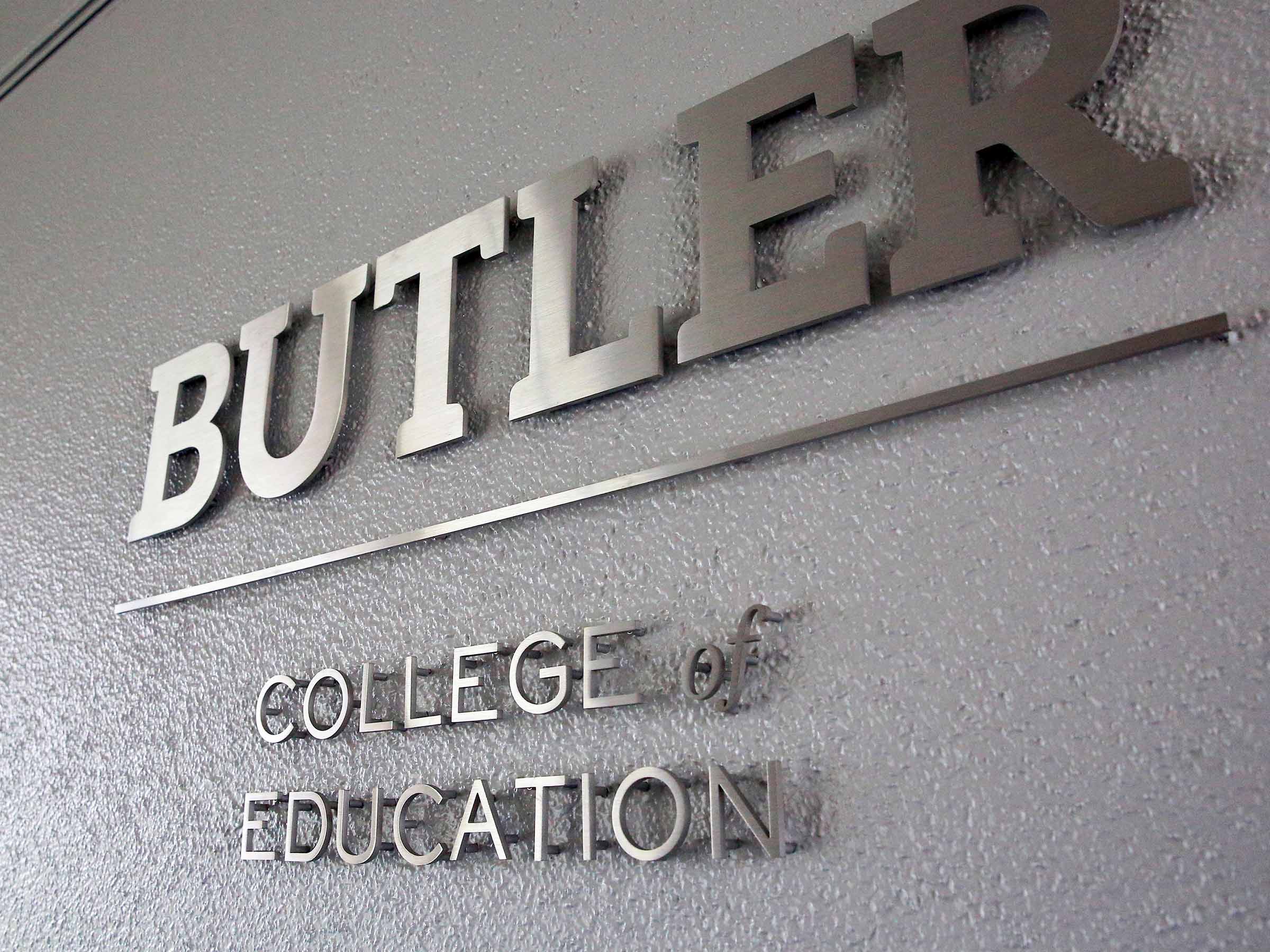 Butler College of Education sign letters shine on a wall.