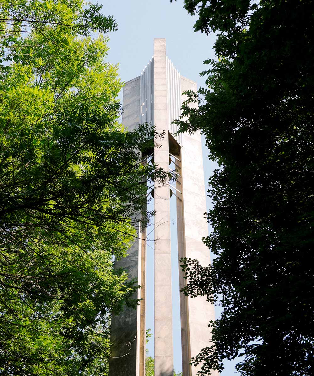 Limestone carillon framed by large shade trees.