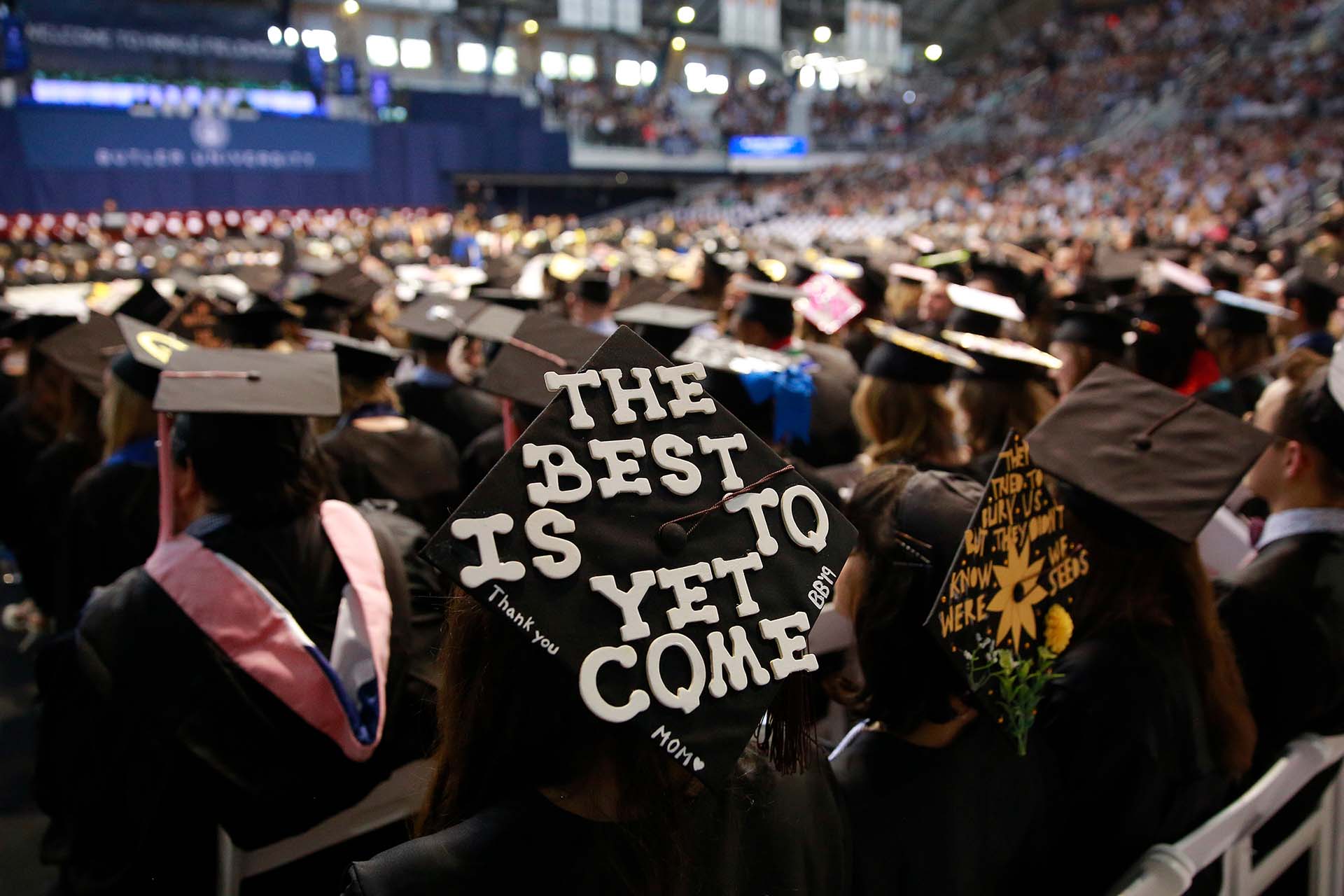 Among the many graduation caps at Butler University Commencement ceremony, one is shown handcrafted with the phrase "The best is yet to come" on it.