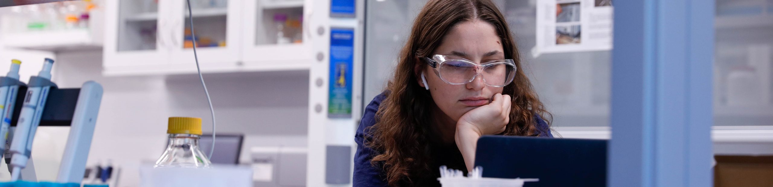 student wearing safety glasses looking at a computer