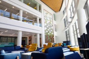 The new Sciences Complex atrium viewed from the ground, looking slightly up at the artwork on the wall in the distance and the floors overlooking the atrium
