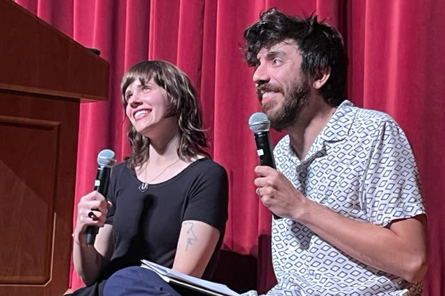 Paige Lewis and Kaveh Akbar smile on stage while holding microphones.