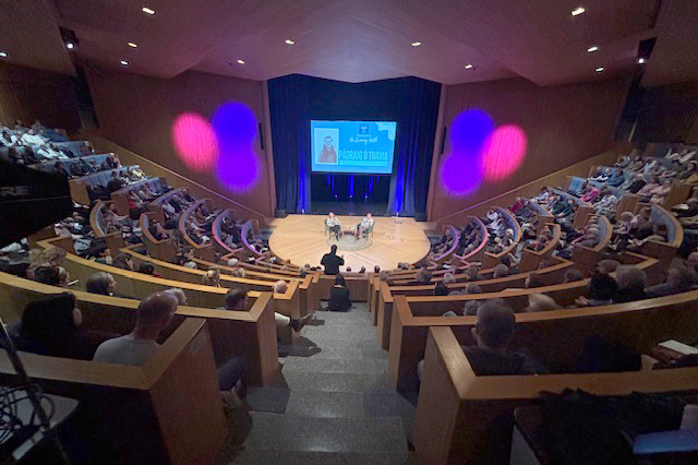 Padraig O Tuama on stage below steep seating of attendees at a reading event in Shelton Auditorium.