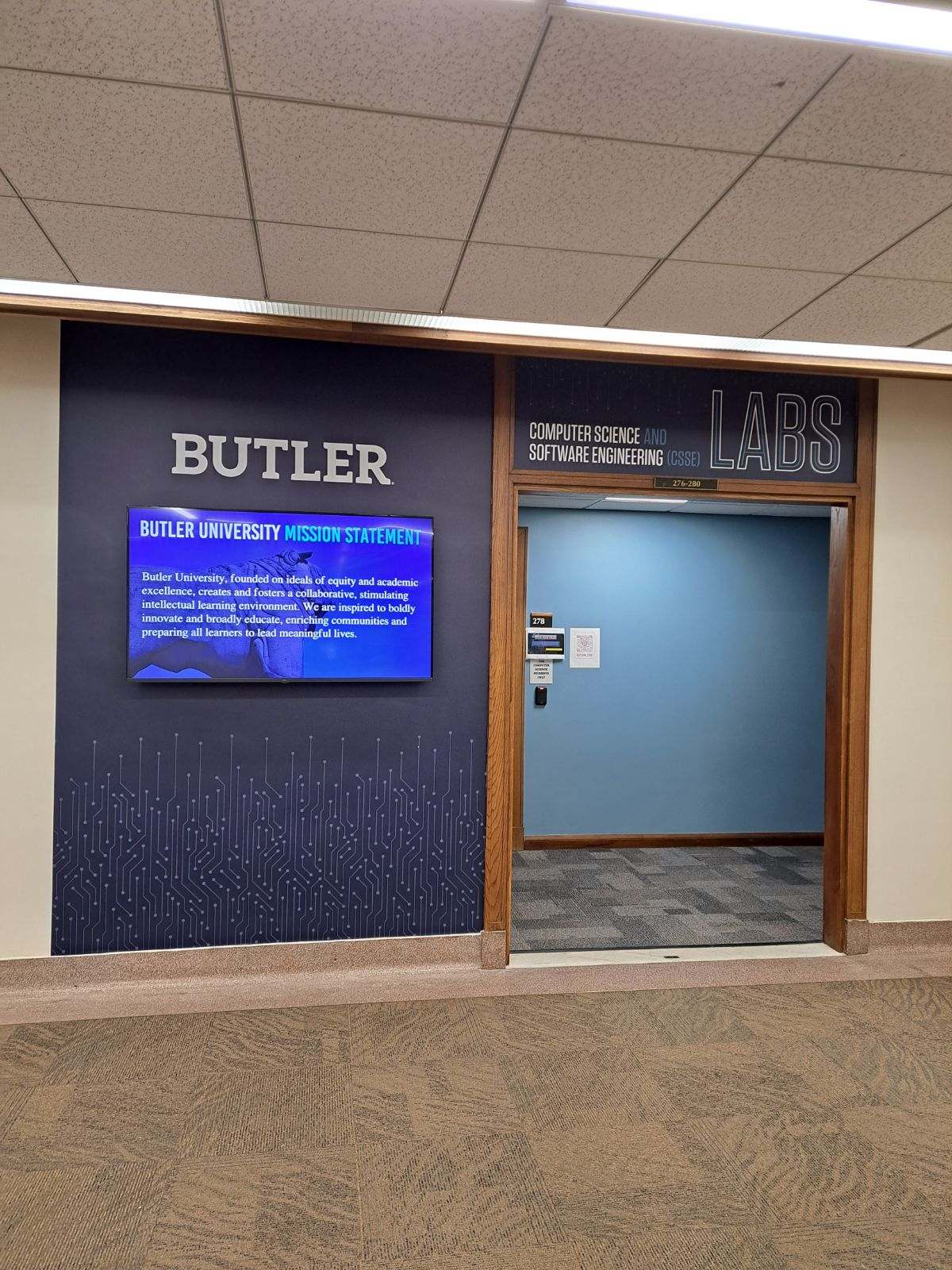 Entrance way to dedicated CSSE lab and classroom space on the second floor of Jordan Hall. A wall-mounted television screen displays the Butler mission statement.