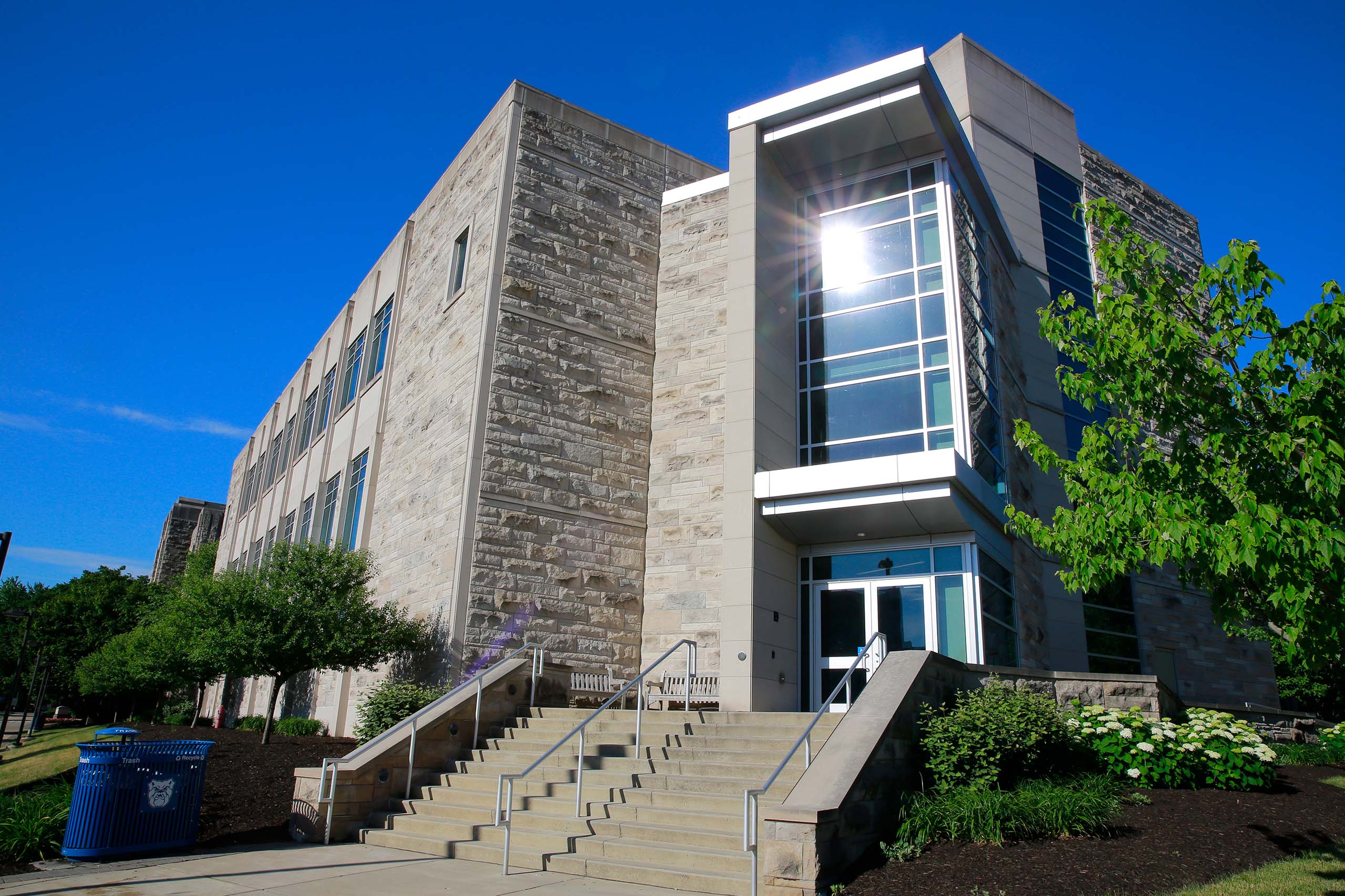 The sun reflects off the large windows of the corner entrance to the Butler University Pharmacy and Health Sciences Building