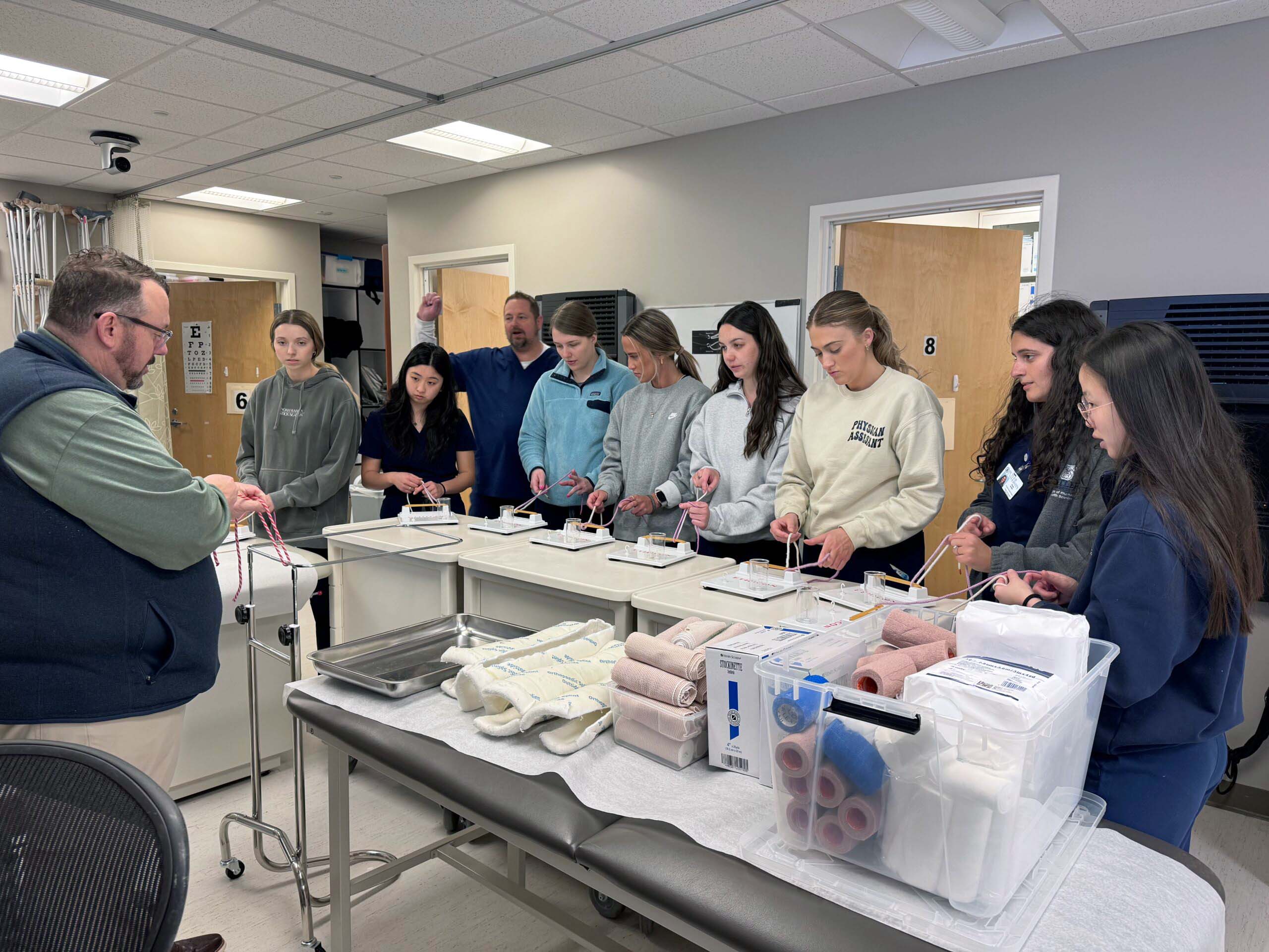 A group of physician assistant (PA) students practice intubation techniques with guidance from a professor.