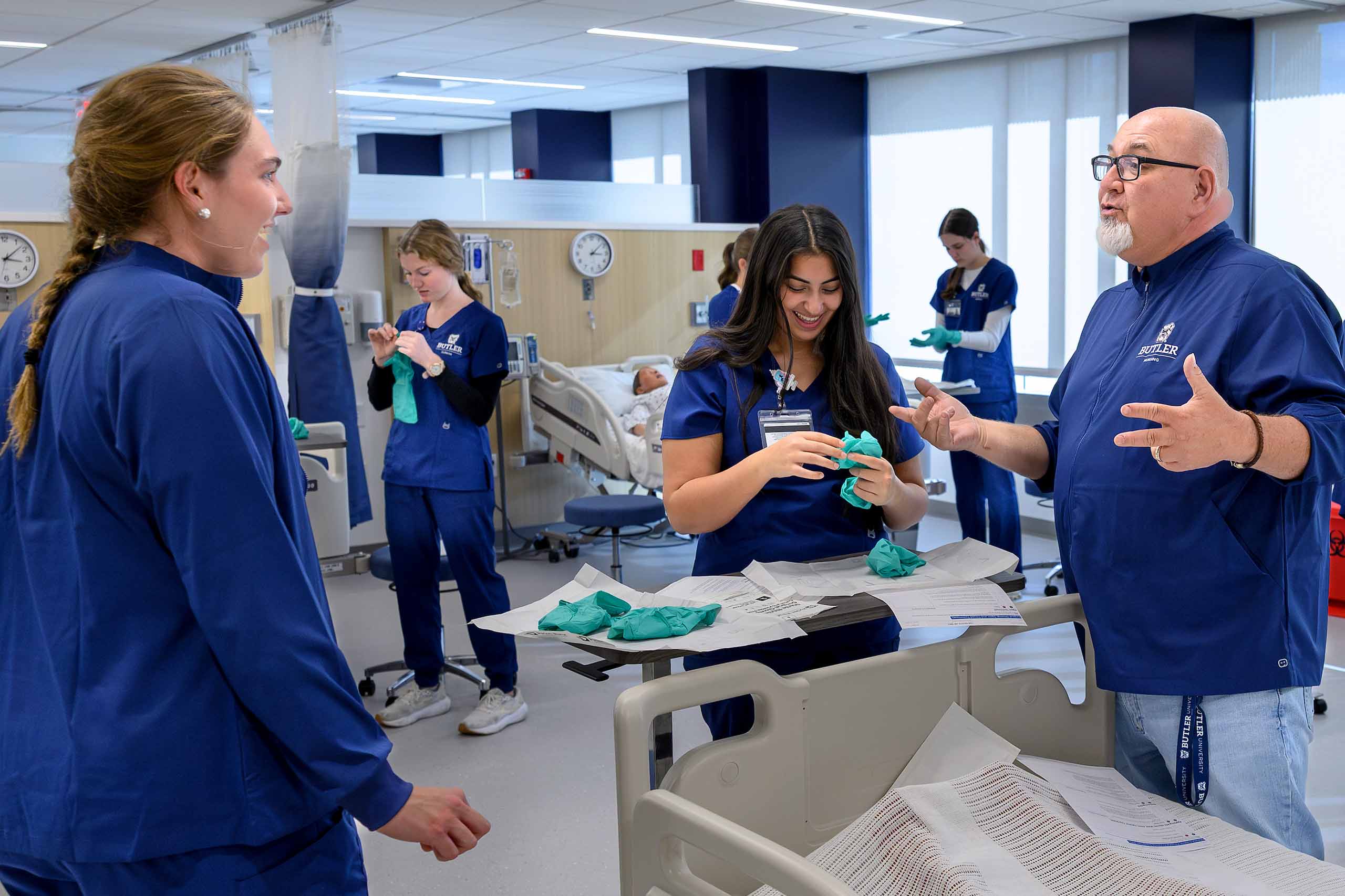 Nursing professor speaking to students while they put on medical gloves.