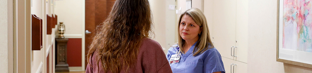Doctor speaks to patient in clinic hallway.