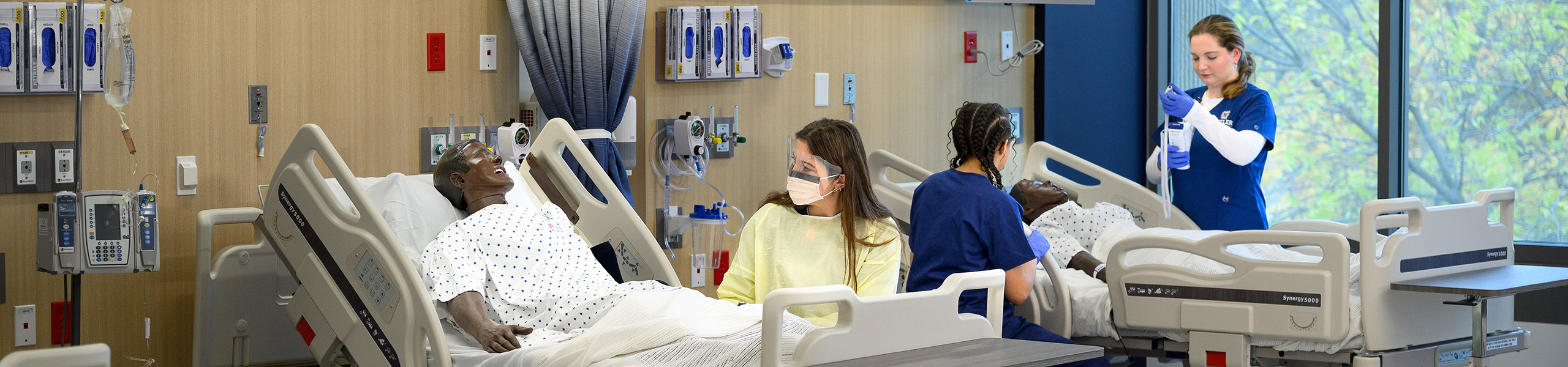 Nursing students work at hospital beds with manikin patients.