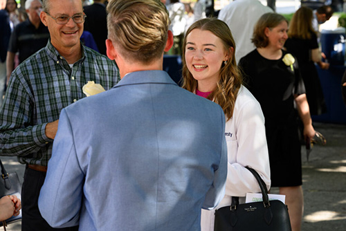 Female student in white medical coat in a chat with two other people.