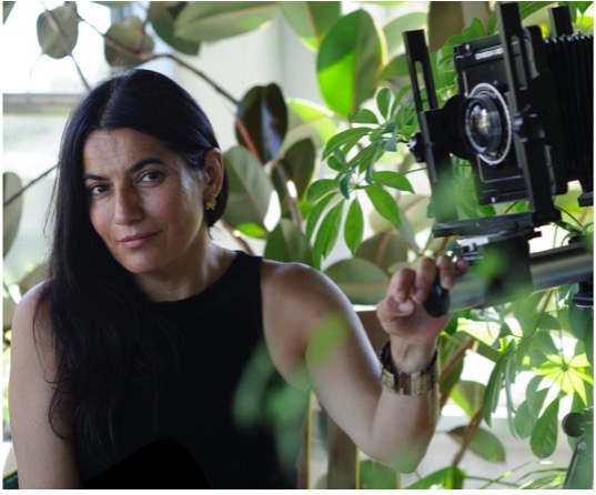 Alexandra McNichols-Torroledo with a camera under a tree.