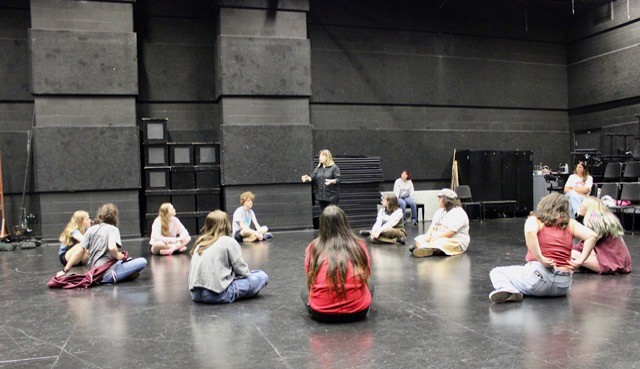 Instructor speaking to group of students sitting on the ground.