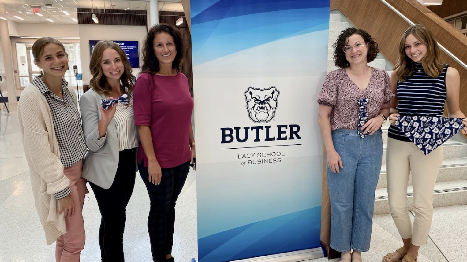 Group of women standing in front of sign in the Lacy School of Business