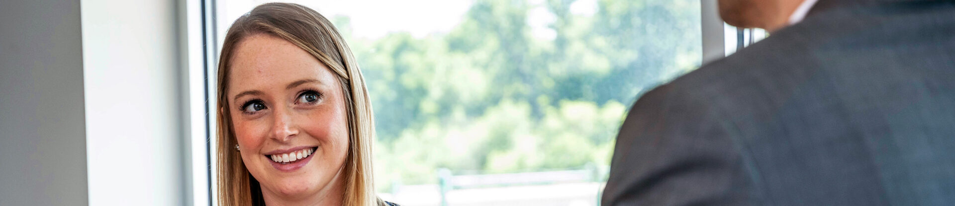 Female accounting student smiles at man in business suit speaking to her.