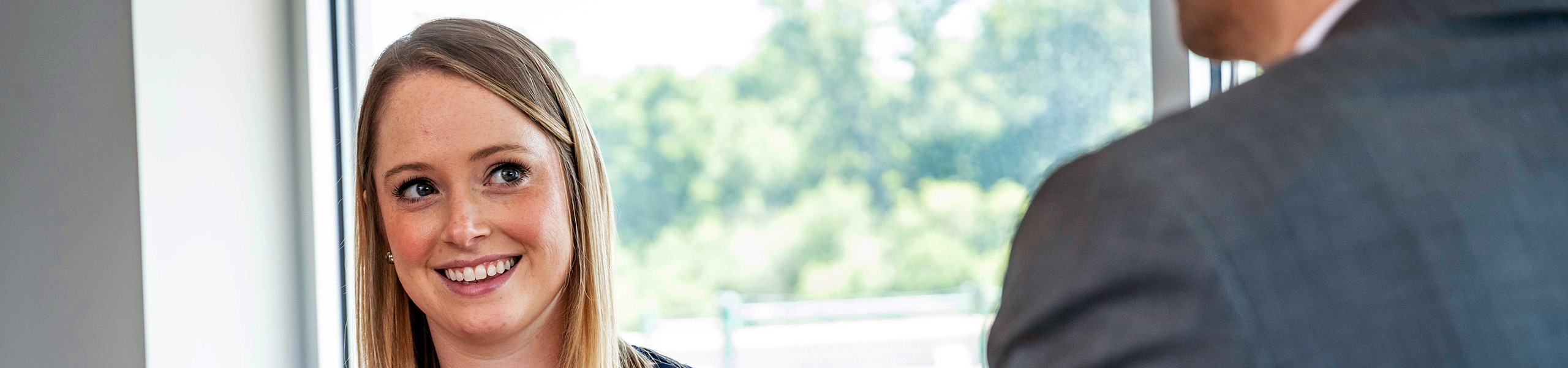 Female accounting student smiles at man in business suit speaking to her.