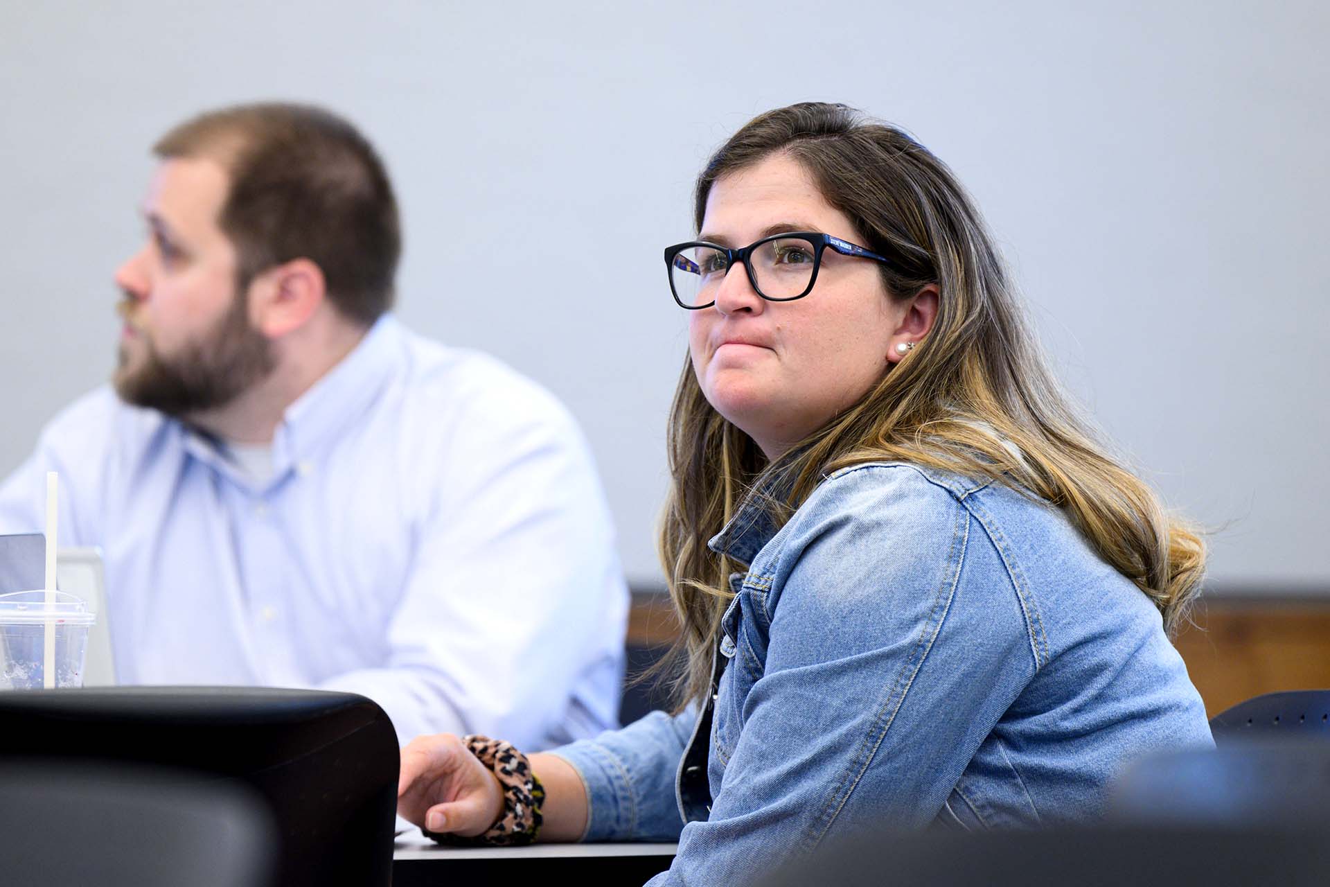 Female student wearing eyeglasses has focused look as she listens to instructor.