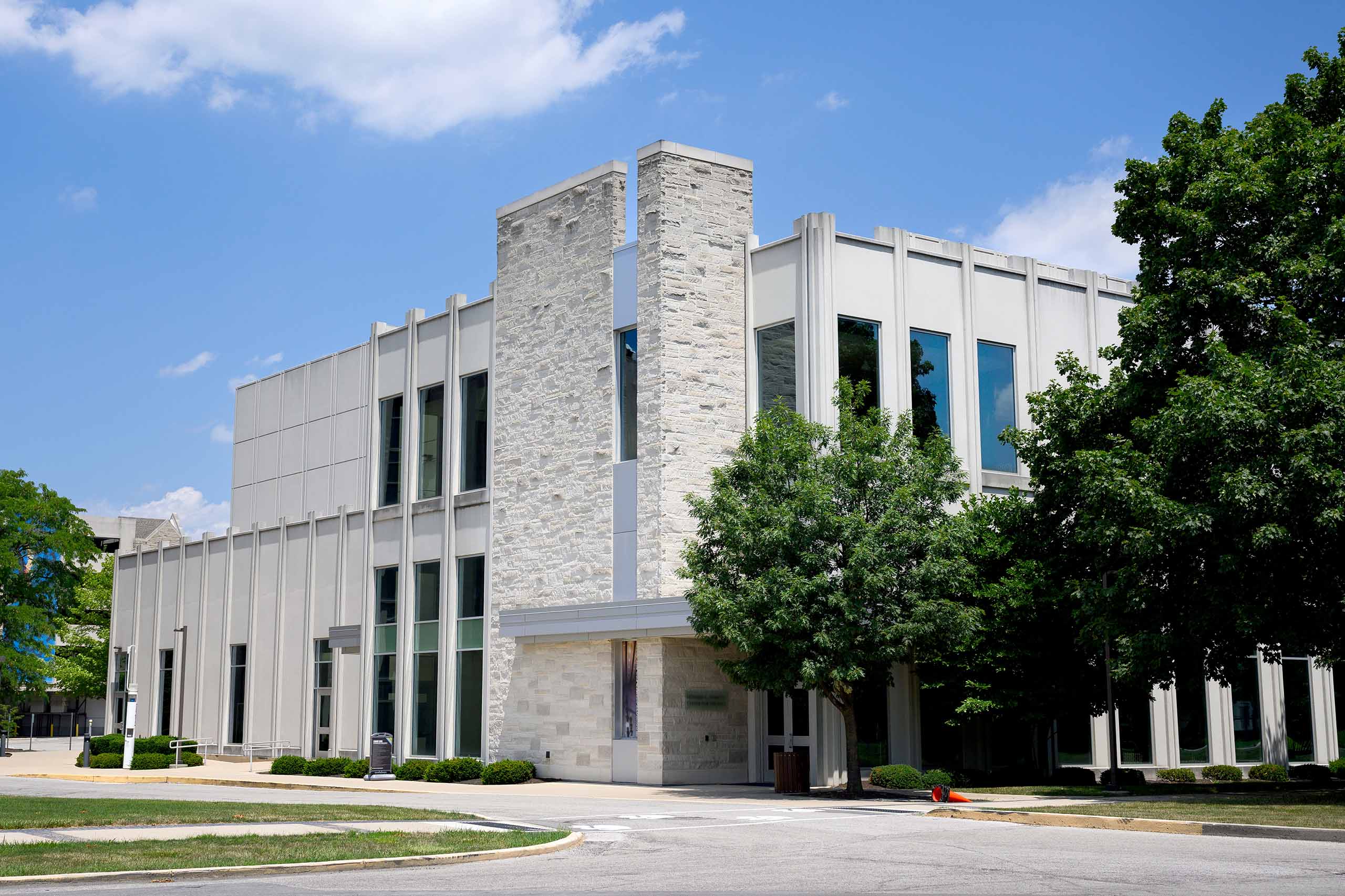 Schrott Center for the Performing Arts limestone exterior and south entrance with shade trees against building.