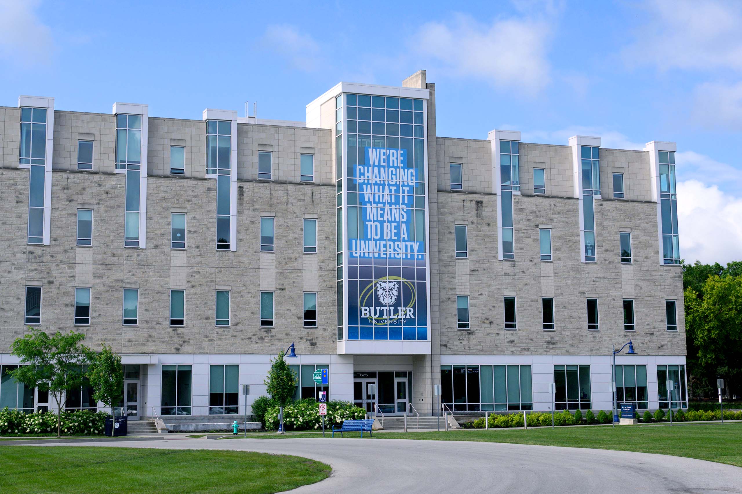 Dugan Hall south entrance with large windows and signage that says, "We're Changing What It Means to Be a University."